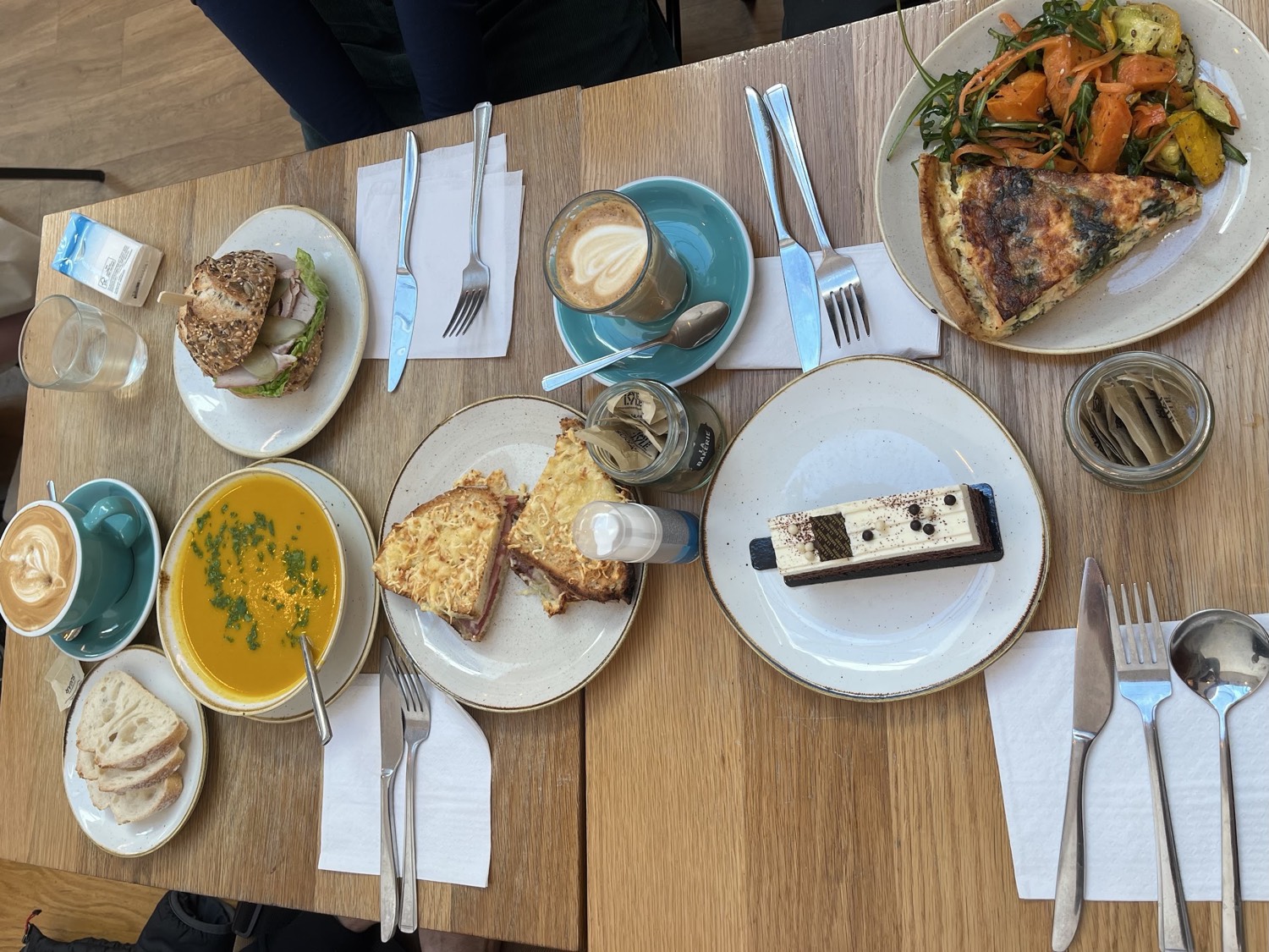 A spread of La Bakerie dishes: quiche with salad, croque monsieur, soup, a chocolate slice and coffees