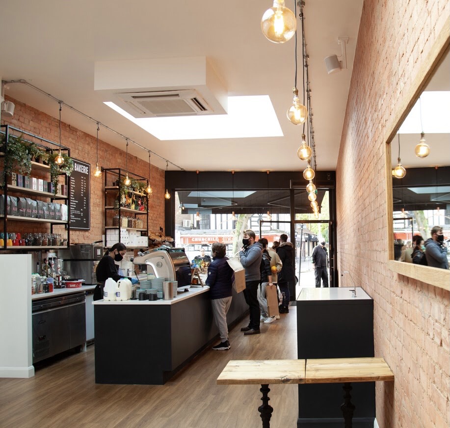 Inside La Bakerie: exposed brick walls, Edison bulbs, the coffee counter and the BAKERIE menu board
